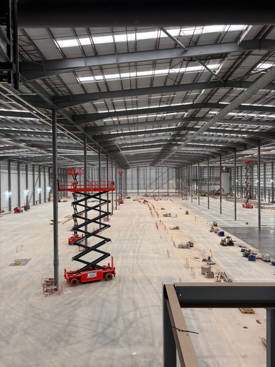 Main hall of the distribution centre during fit-out, with scissor lifts working at height