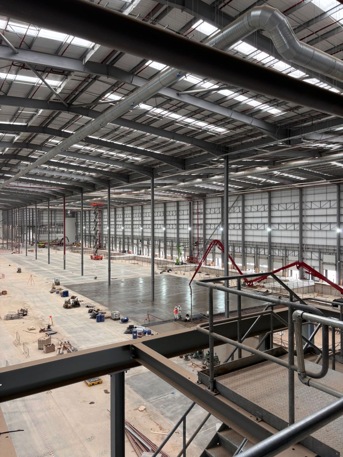 Interior of a new distribution centre in Doncaster with floor slab works in progress, viewed from a mezzanine