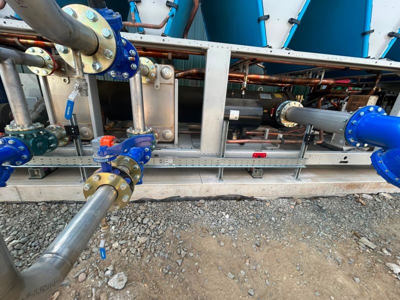 Perforated cable tray fixed below pipework at the base of external plant